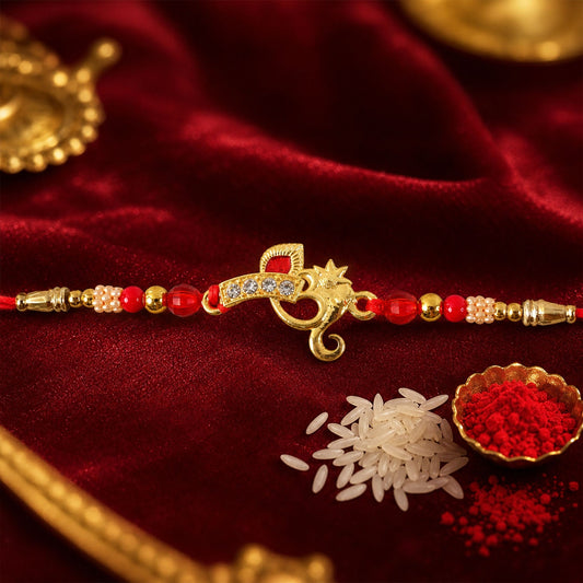 A gold-colored Om symbol with clear stones and red enamel on a red thread with red and gold beads, on a red velvet