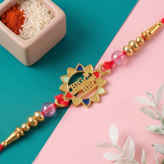 A gold-toned 'Big Bro' charm with multicolor enamel, pink beads, and gold accents rests on a red thread.