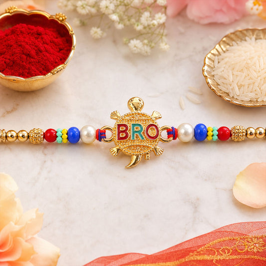 A gold-colored turtle charm with "BRO" in red and teal letters is centered on a beaded bracelet with pearls, gold, red,