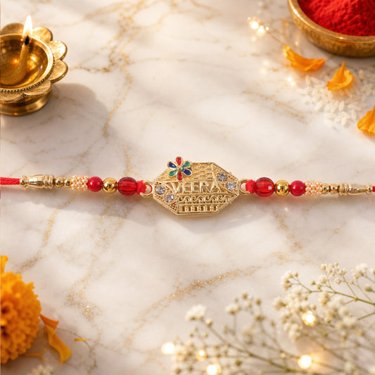 A gold-colored Veera text stone Kundan beaded bracelet with red thread and beads is displayed on a marble surface with