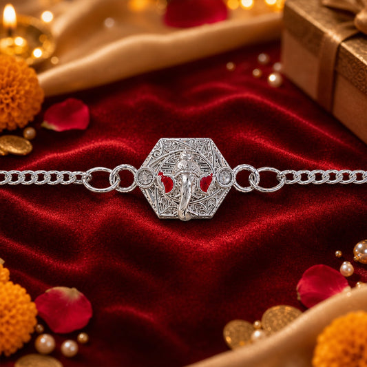 A silver chain bracelet with a hexagonal Ganesha charm is centered on a red velvet cloth, surrounded by festive decor.