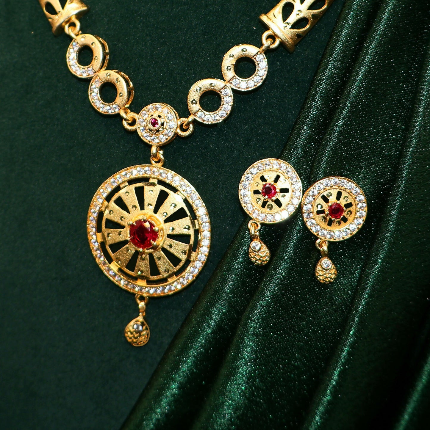 Close-up of round pendant with ruby center, CZ stones, and black enamel detailing