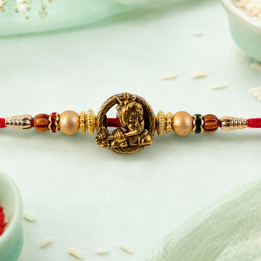 Close-up of Kanha Name Devotional Rakhi with golden flute detail and red thread.