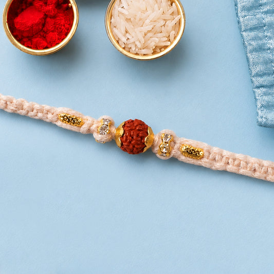 Silver style Rakhi with soft pastel beads and intricate stone detail on a clean background.