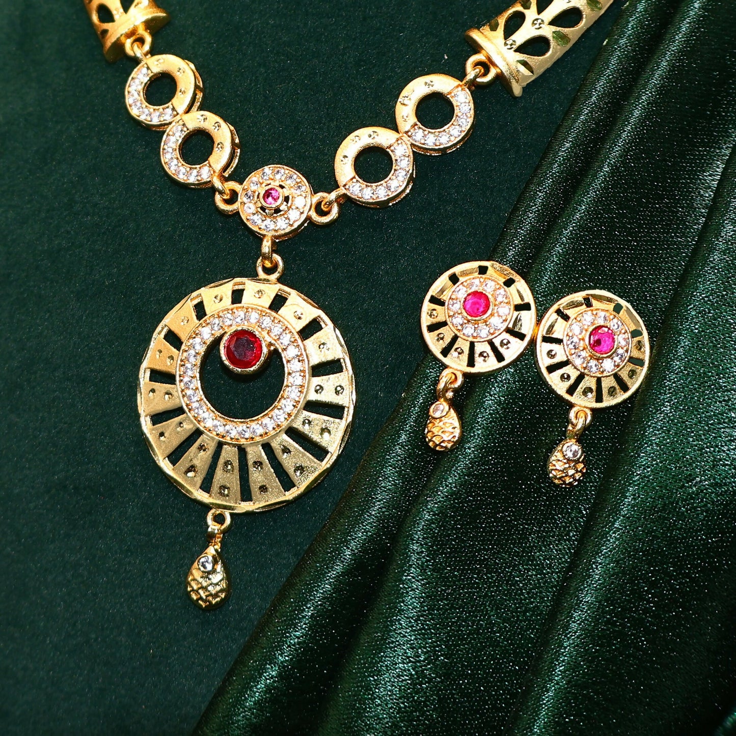 Matching gold plated earrings with circular design and ruby stone accents
