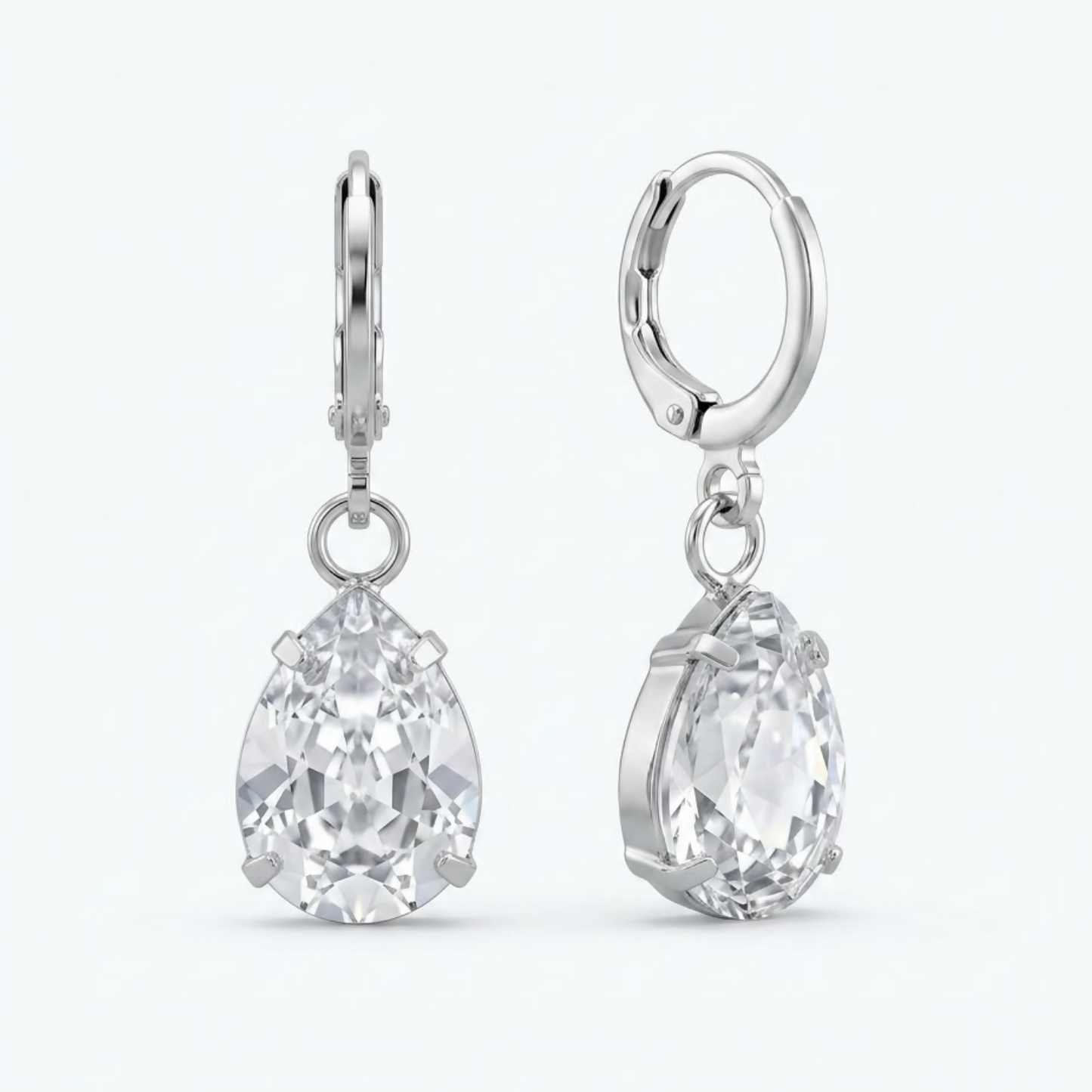 A pair of silver teardrop crystal earrings with clear faceted stones are displayed on a white background.