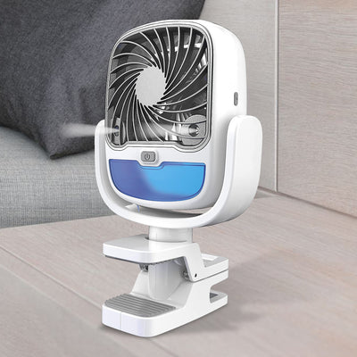 A white and blue portable clip-on air cooler stands on a light wooden surface, emitting a fine mist.