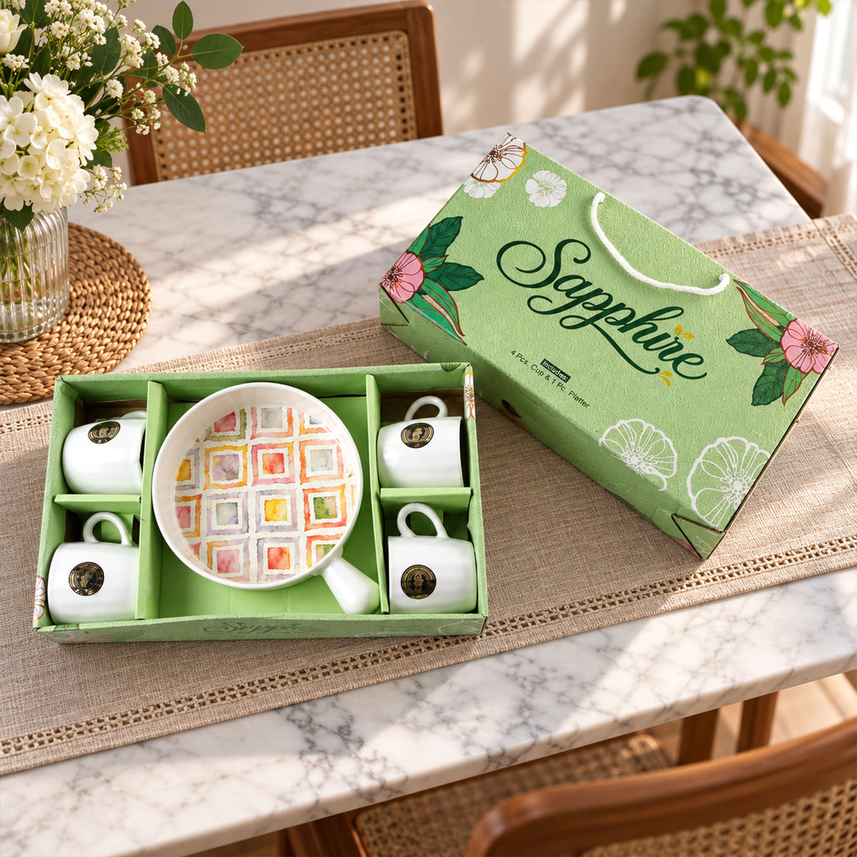 A five-piece ceramic set, including four white mugs and a platter with a colorful square pattern, in a green gift box.