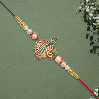 Elegant Peacock Design Rakhi with Pearl Beads and Golden Detailing on Red Thread