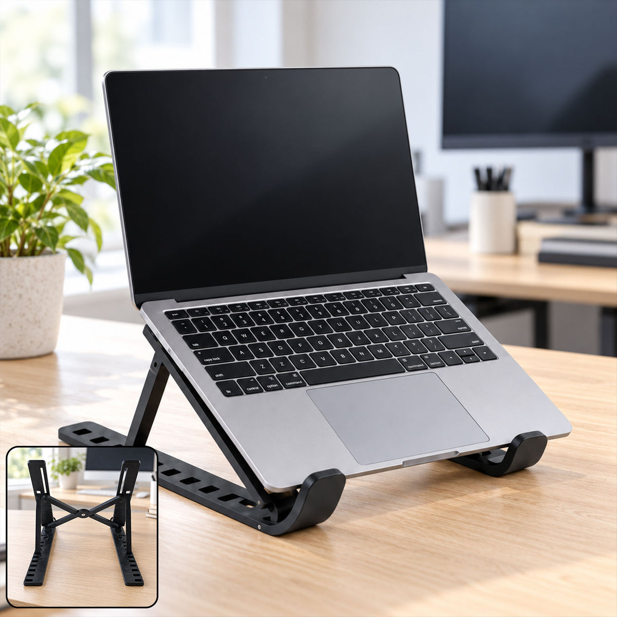 A silver laptop is positioned on a black adjustable stand on a wooden desk, with an inset showing the stand's folded form.