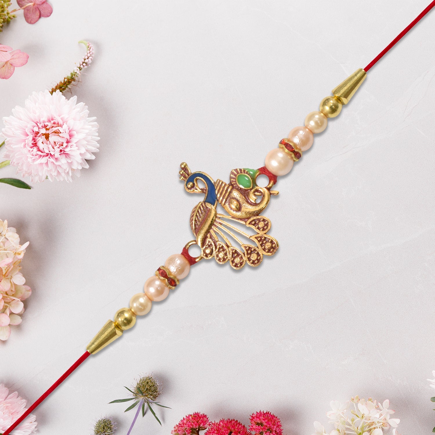 Elegant Peacock Design Rakhi with Pearl Beads and Golden Detailing on Red Thread