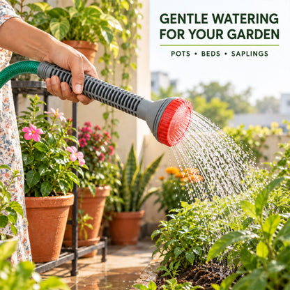 A person's hand holds a grey and red nozzle, watering green plants in terracotta pots on a patio.