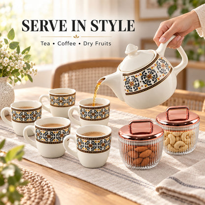 A hand pours tea from a white ceramic teapot into a cup, surrounded by five other cups and two jars with nuts.