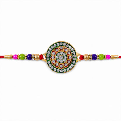 A gold and green circular Rakhi with clear stones and colorful beads is centered on a plain white background.