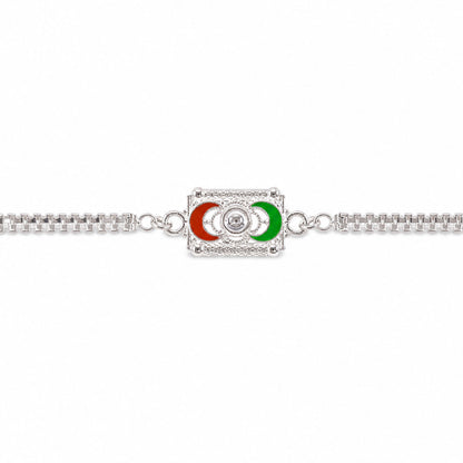 A silver-colored bracelet with a rectangular centerpiece featuring red and green crescent moon shapes, centered against a