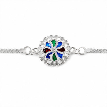 A close-up of a silver chain bracelet with a round, colorful enamel and crystal centerpiece, centered horizontally on a