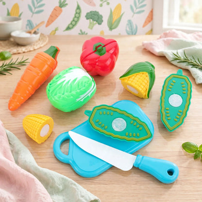 A collection of colorful plastic vegetables, a blue chopping board, and a white toy knife on a wooden surface.