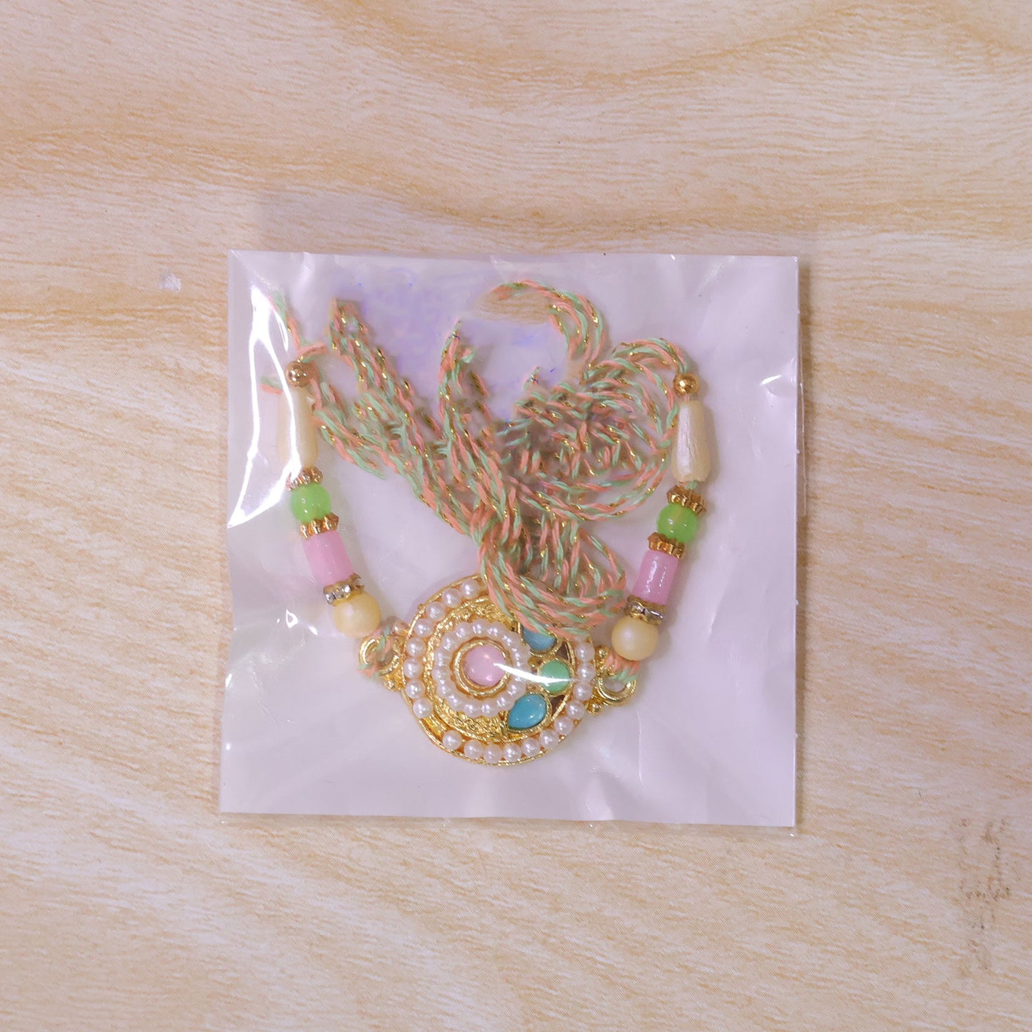 Pearl Bordered Round Pendant Rakhi with Turquoise and Pink Center