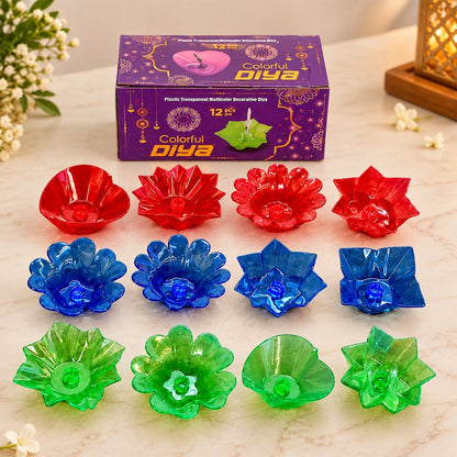 A purple box of 12 colorful diyas, with red, blue, and green plastic diyas arranged around it.