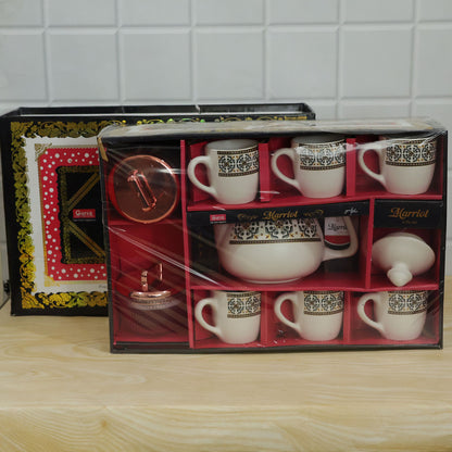 A Marriot gift box, open and shrink-wrapped, displays a white ceramic tea set with six cups, a teapot, and two jars.