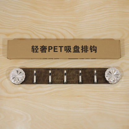 The gray transparent wall rack with five silver folding hooks and a brown cardboard box with Chinese characters on a light