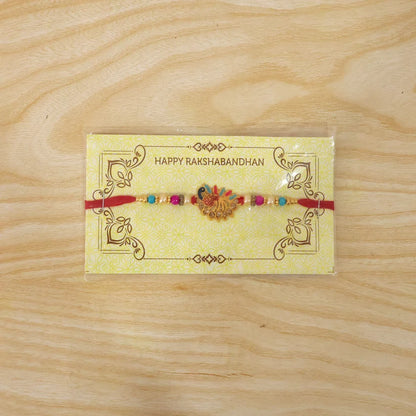 Peacock Rakhi – Colorful Stone Detailing with Red Thread
