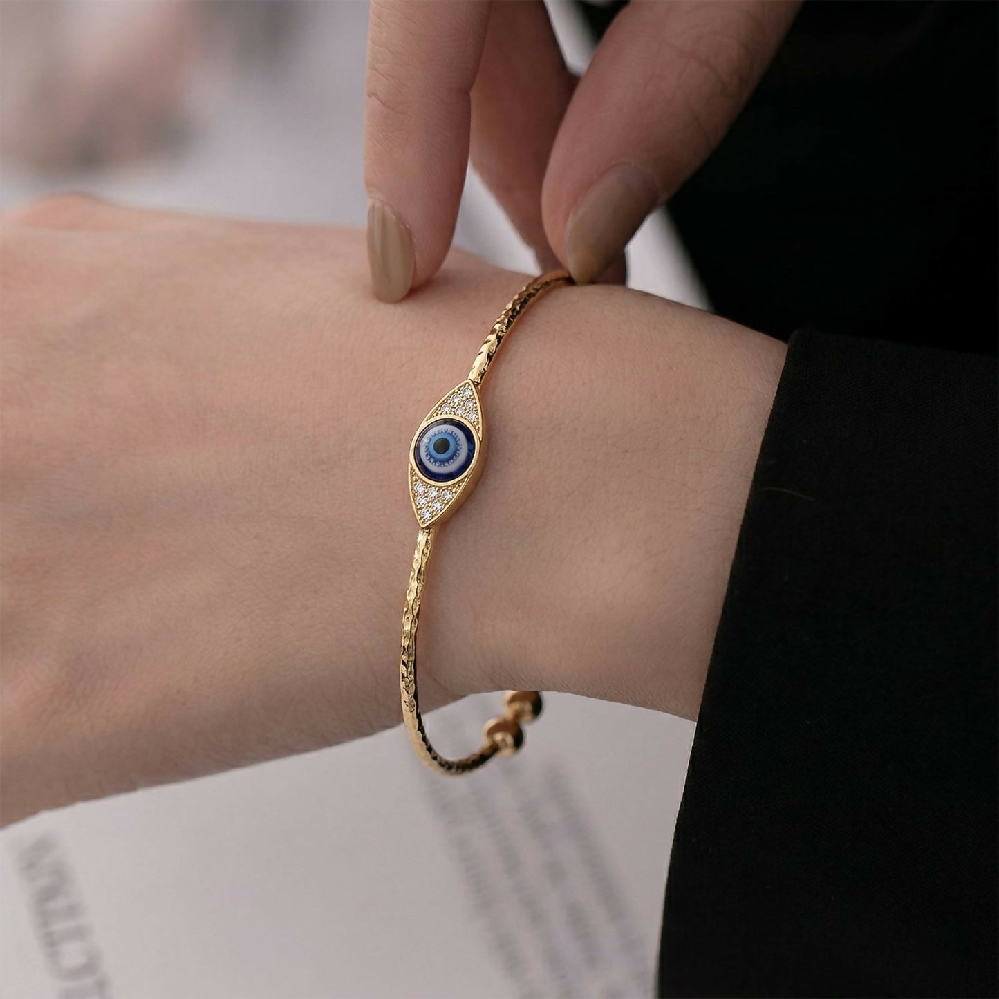 Stacked gold evil eye adjustable bangles showcasing textured finish