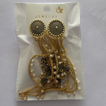 Gold tone jhumka earrings with pearl drops and chains against a subtle background