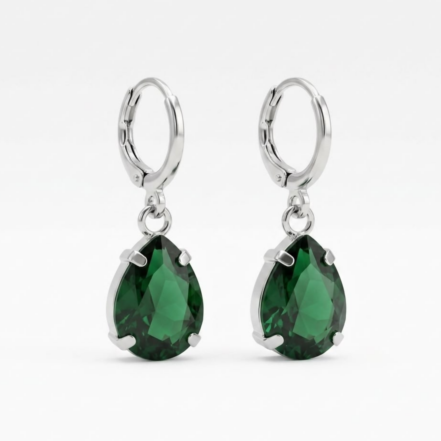A pair of green teardrop crystal earrings with silver hooks on a plain white background.