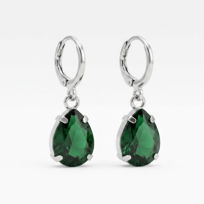 A pair of green teardrop crystal earrings with silver hooks on a plain white background.