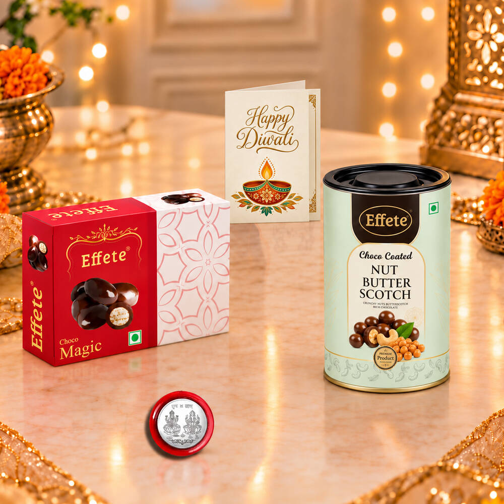 Red chocolate box, nut butterscotch tin, silver coin, and greeting card on a marble table with blurred background.