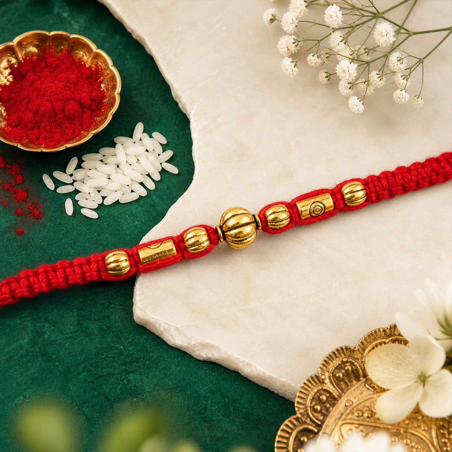 Red Braided Rakhi with a Row of Smooth Golden Bead Accents