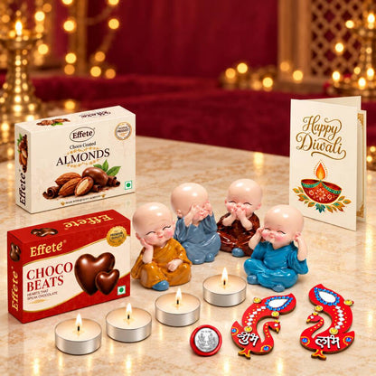 A festive hamper box with two chocolate boxes, four Buddha figurines, tealights, and decor on a white surface.