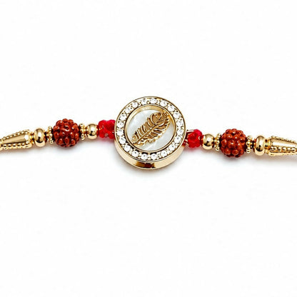 A close-up of the golden feather dial with crystal halo and rudraksha accents on a plain white background.
