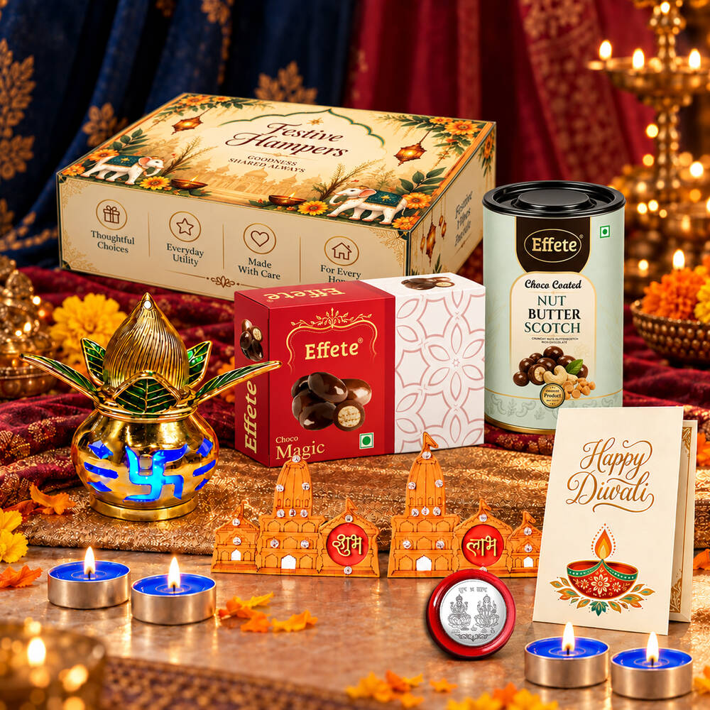 A Diwali gift set with a decorative box, sweets, a golden diya, and tealights, arranged on a red and gold patterned cloth.