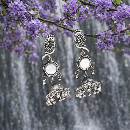Front view of silver oxidised peacock jhumka earrings highlighting mirror-style centre element