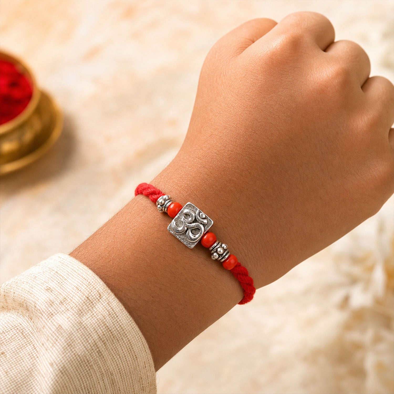 Red Thread Rakhi with a Bold Silver Om Pendant and Red Beads
