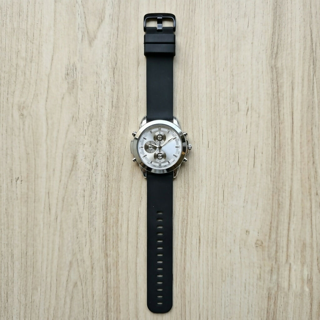 Watch displayed with its black silicone strap unclasped