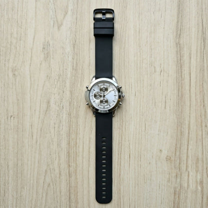 Watch displayed with its black silicone strap unclasped