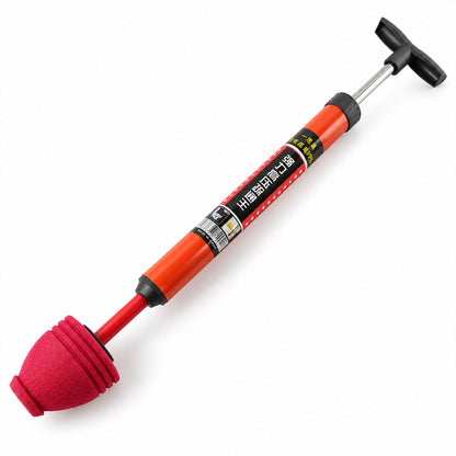 An orange and red pump plunger with a black T-handle and ribbed foam cup rests on a white surface.