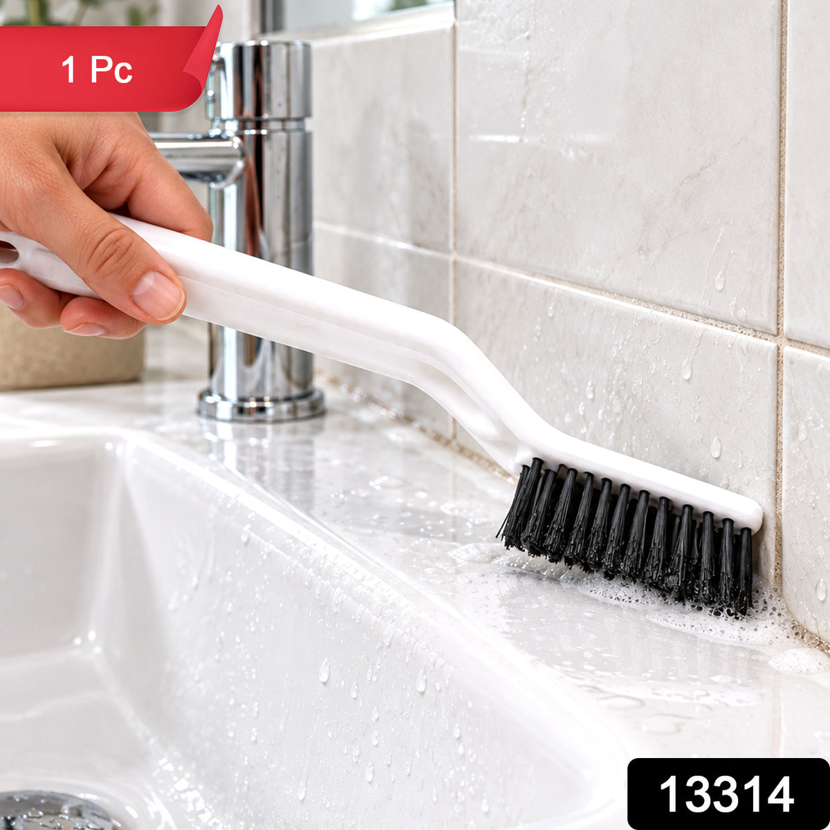 A person's hand holds a white cleaning brush with black bristles, scrubbing a white tiled surface.
