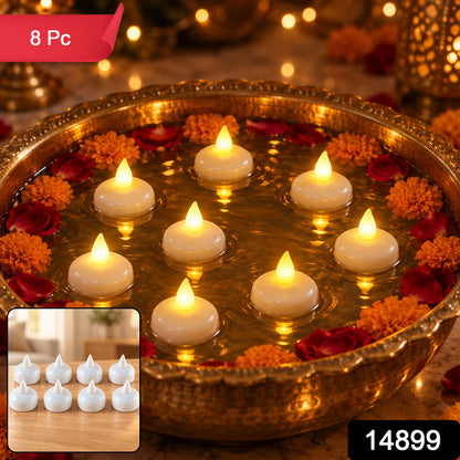 A brass bowl holds eight white floating LED diyas, surrounded by orange marigolds and red rose petals, with a blurred