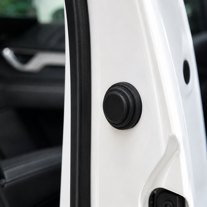 A black rubber shock absorber is installed on the white frame of a car door, with the car interior visible in the background