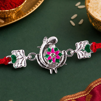 Silver Peacock Flower Heart Rakhi with dori, a traditional design for Raksha Bandhan.