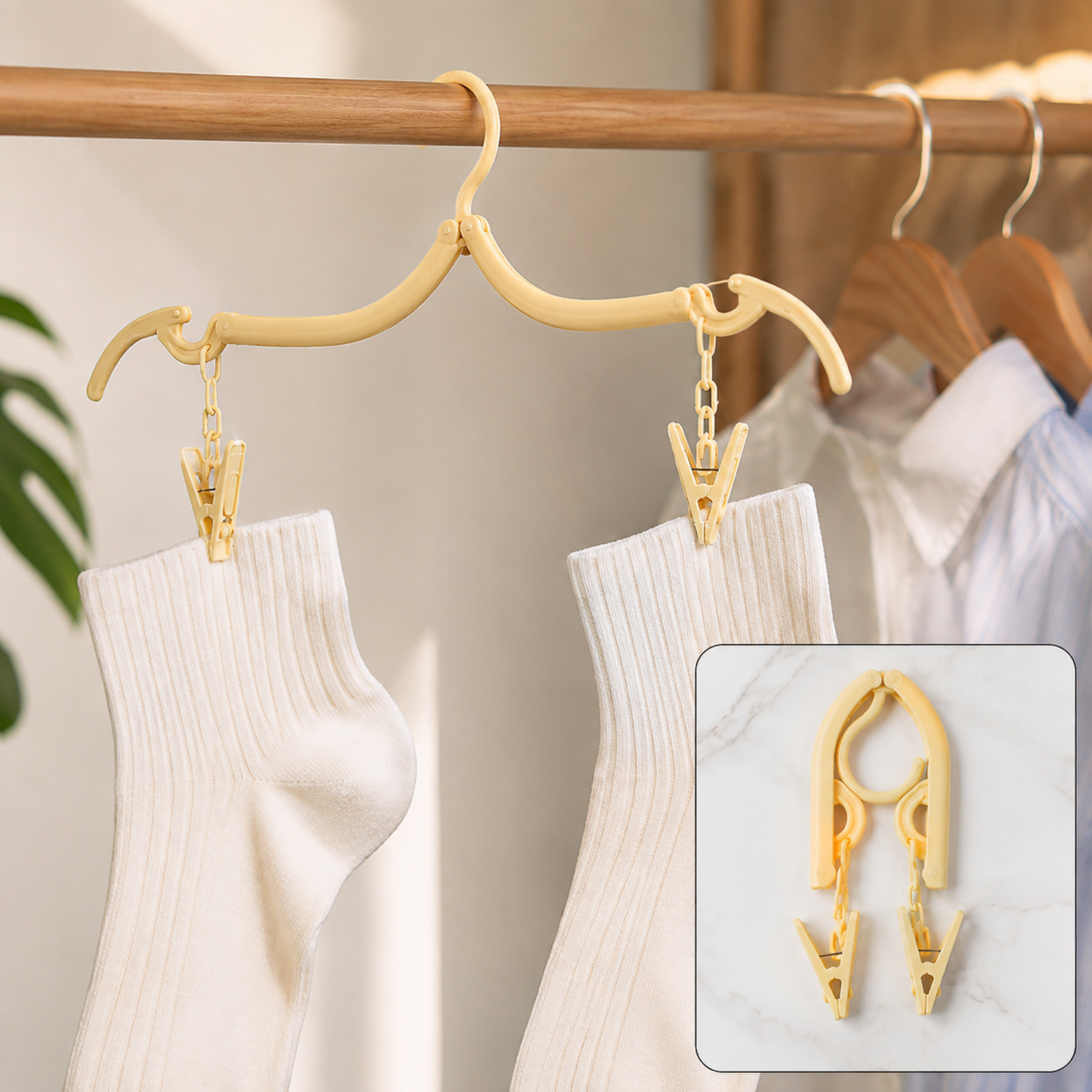 A beige foldable clothes hanger with two clips holds two white socks on a wooden rod with other clothes.