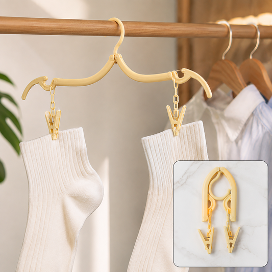 A beige foldable clothes hanger with two clips holds two white socks on a wooden rod with other clothes.