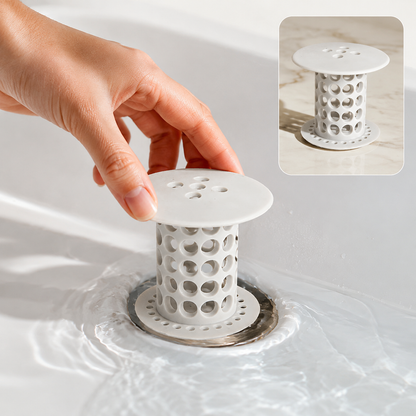 A hand inserts a white silicone tub drain hair catcher into a chrome drain in a white sink with water. The inset shows the
