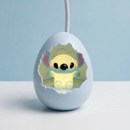 A light blue cracked egg lamp with a glowing Stitch figure inside, against a plain blue background.