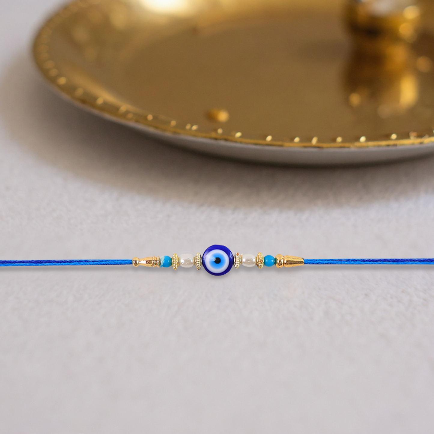 Stylish Blue Thread Rakhi with Central Stone, Pearl Beads, and Golden Detailing – Elegant Bracelet for Raksha Bandhan