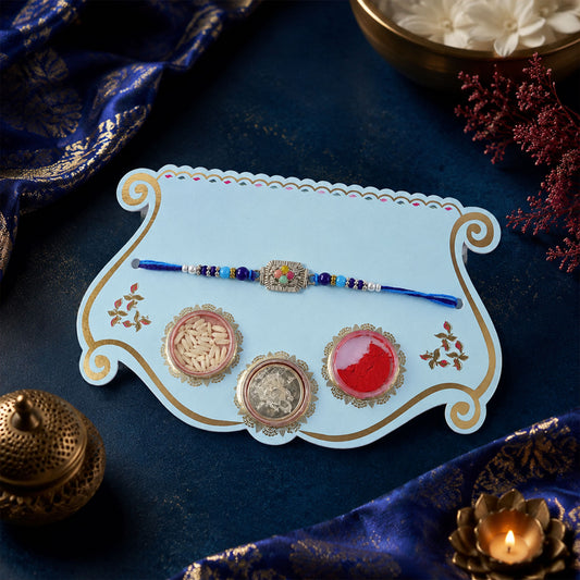 Silver Floral Stone Rakhi with Royal Blue Thread, Roli Chawal Coin and Card Gift Packing